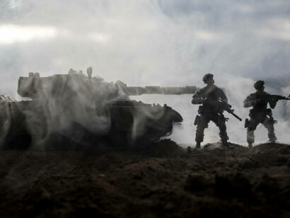 A dramatic scene of World War II unfolds with soldier silhouettes and armored vehicles fighting beneath a cloudy, sunset-lit sky