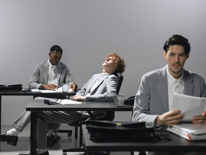 A group of men in an office, silent and independent, their purpose no longer shared