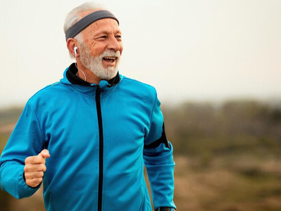 A senior man running outdoors with earphones in, enjoying the rhythm of his music as he stays active and healthy