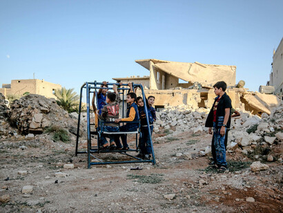 Poor children play among the ruins of a destroyed city, surrounded by the devastation left behind by war
