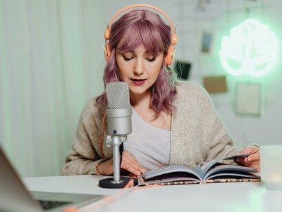 A woman records a podcast from a cozy indoor studio, sharing insights from a book with her audience