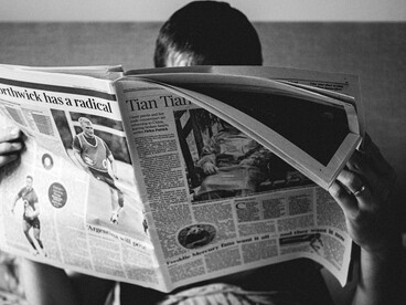 Un lector absorbido por la lectura de su periódico, simbolizando el poder de la censura y la manipulación de los medios