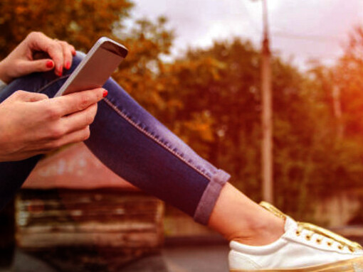 A girl on the sidewalk, engrossed in her social media on her phone