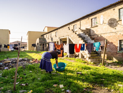 A woman in Langa township, Cape Town, South Africa, diligently hangs laundry, symbolising the daily quest for dignity and basic necessities highlighted in the UN Declaration of Human Rights