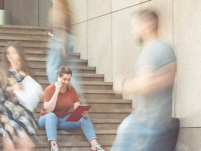 A woman on the street talking on the phone, surrounded by fast-moving people, symbolizing modern society's rush and the relentless march of time