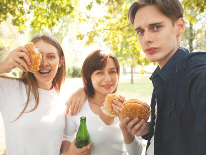 Friends enjoying burgers and beer at the park, snapping selfies amidst the fun