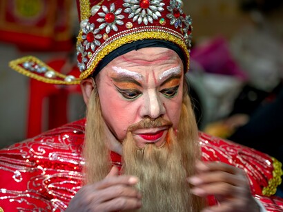 An opera performer carefully adjusting his costume before the performance, representing the fragile boundary between cherished dreams and everyday reality