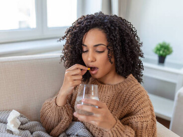 A woman swallows a joint health supplement as part of her routine for managing knee discomfort