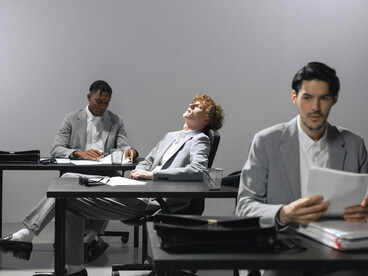 A group of men in an office, silent and independent, their purpose no longer shared