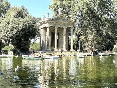 Visitors in boats on the lake, with the Temple of Aesculapius in Villa Borghese Park, Rome, Italy