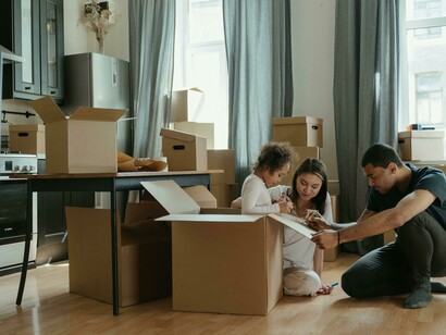 Parents and children opening boxes together in a cluttered living room after relocating