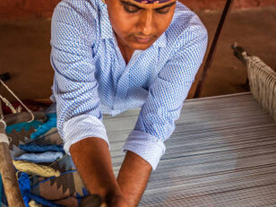 An Indian man weaving textiles on a traditional handloom in Rajasthan
