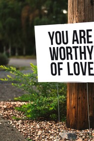 Love yourself. A reminder in the forest to practice self-love, that reads "You are worthy of love""