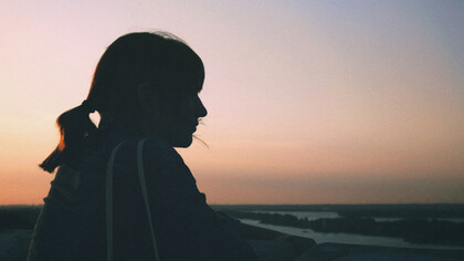 Mujer contempla el atardecer frente a la playa