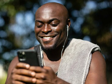 A man checking his phone while outside, symbolising the convenience of managing money digitally
