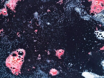 Delicate pink foam bubbles drifting on a dark, serene water surface