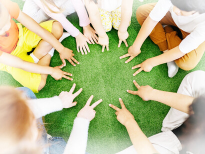 A group of children putting in both hands with two fingers in the circle