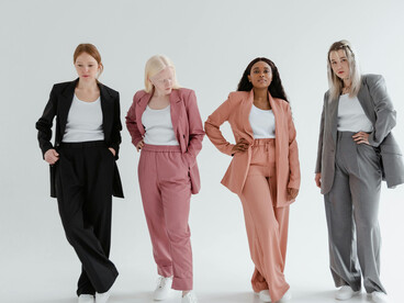 Women dressed in business coats posing against a white background