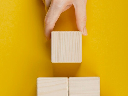 As the hand stacks the wooden blocks, it symbolises the thoughtful process of evaluating and prioritising solutions based on their feasibility and impact