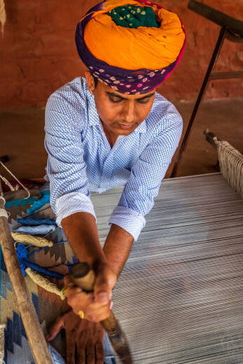 An Indian man weaving textiles on a traditional handloom in Rajasthan