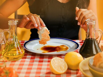Mulher molha pão em azeite balsâmico. Como em qualquer preparo na cozinha, o tempero é o que vai deixar tudo mais especial. Experimente usar vinagres ou limões diferentes, como o limão caipira e o siciliano ou o vinagre balsâmico. Outros ingredientes como mostarda, tahine e até mesmo ervas frescas como salsa e manjericão vão trazer um toque muito original e elevar o nível de qualquer salada