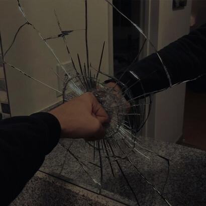 A person filled with anger and frustration shatters a mirror with a forceful blow