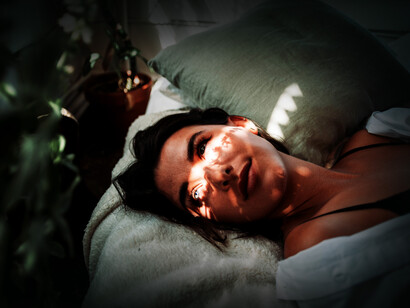 Chica acostada mira hacia el reflejo de luz que toca su rostro