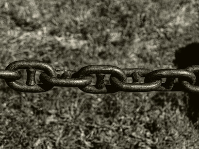 Heavy iron chains stretched across the ground evoke the physical restraint of enslaved labor, a system that generated wealth while enforcing total control over Black bodies