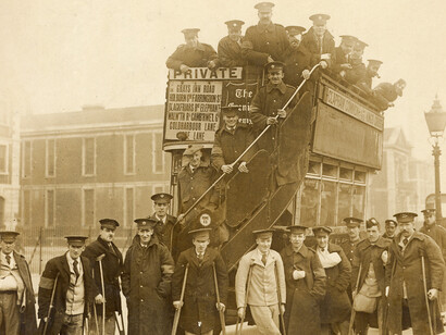 Group of wounded soldiers, most on crutches, at rear of B-type bus, with others posed on staircase and upper deck