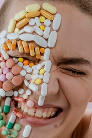Happiness on a person's face that also has a collection of pills