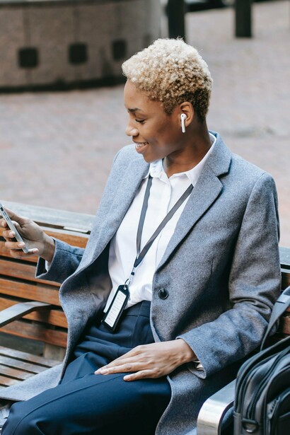 A woman sat on a bench looking at a mobile phone