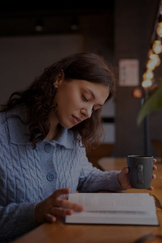 Woman relaxing in a cafe, reading a book and sipping tea