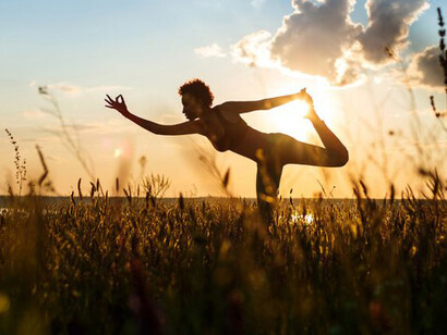 A girl’s silhouette practicing yoga in a peaceful field at dawn, capturing the essence of mindfulness and meditation while harmonizing with the natural surroundings