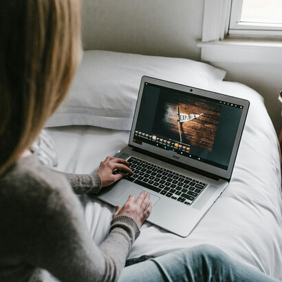 A woman sitting on her bed with a laptop; blue light damages sleep quality and, in turn, affects overall health