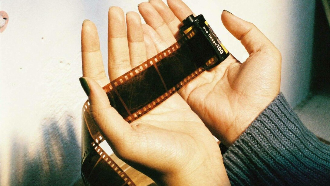 Mani attente e delicate avvolgono la pellicola cinematografica, come a proteggere storie, ricordi e sogni racchiusi in ogni fotogramma