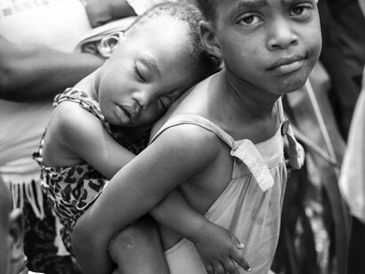 A child labouring a younger sister on her back as she heads for work