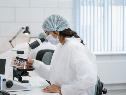 Female researcher in a face mask using a microscope in a modern AI-driven lab