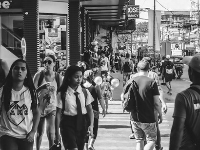 Explore societal dynamics in Dumaguete, Central Visayas, Philippines through a captivating grayscale photo capturing people walking on the street, offering a unique glimpse into the local community