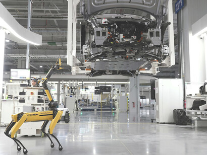 A Boston Dynamics robot navigates a car factory floor, demonstrating the integration of advanced robotics into modern automotive manufacturing
