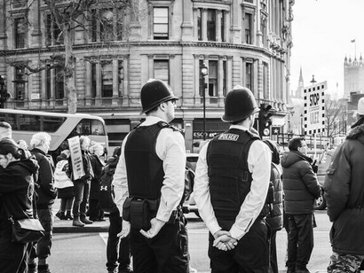 Policía observa a manifestantes que  exigen justicia social y respeto a los derechos humanos, R. U.