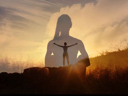 Happy young woman lifting her arms up standing on mountain feeling inspired and in a positive state of mind
