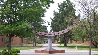 Alistair Bevington (1926–2021). Una escultura titulada «Sundial», erigida en 1968 en el campus del RIT. El reloj de sol es más o menos preciso. Esta imagen se tomó a las 15:30 hora local (hora del este de EE. UU.); el reloj de sol marca aproximadamente las 14:15 debido al horario de verano y a la variación natural de la trayectoria del sol