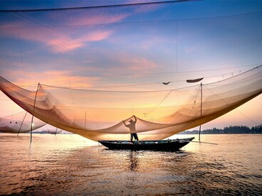 A fishermen casting their nets at twilight, reflecting the simple dignity of lives shaped by the ocean