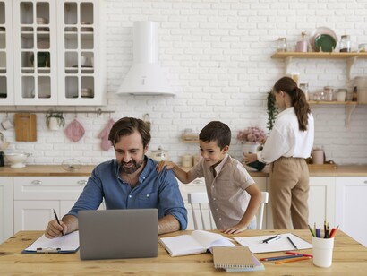 A concentrated father with a laptop next to his smiling kid underscores how remote work brings family moments into the workday, blending care and career in an upbeat, adaptable rhythm