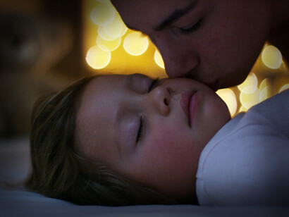 Madre che dà il bacio della buonanotte al figlio addormentato