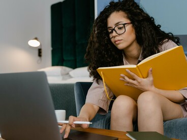 De óculos, uma mulher permanece concentrada diante do laptop enquanto acompanha o conteúdo exibido na tela. A leitura digital exige mais do que decifrar palavras: pressupõe atenção, seleção de informações e capacidade de avaliar criticamente aquilo que se encontra no ambiente virtual