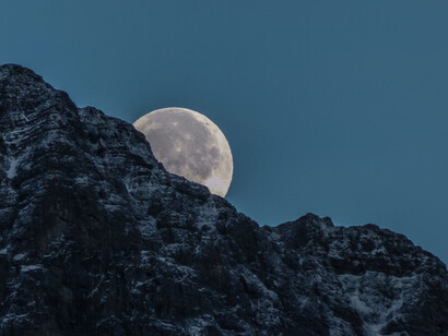 Moon behind rock mountain
