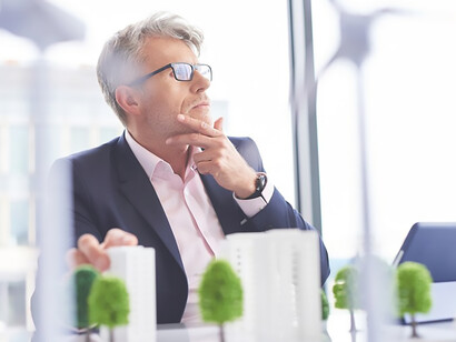 A busy businessman contemplates innovative solutions amidst the backdrop of society, ecological sustainability, and global crises, reflecting the urgency of current challenges