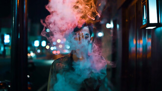 A figure, cloaked in a sleek black leather jacket, exudes an air of cool nonchalance as wisps of smoke curl around him, completing the scene with an edgy allure