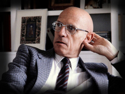 Michel Foucault sitting in front of a bookcase